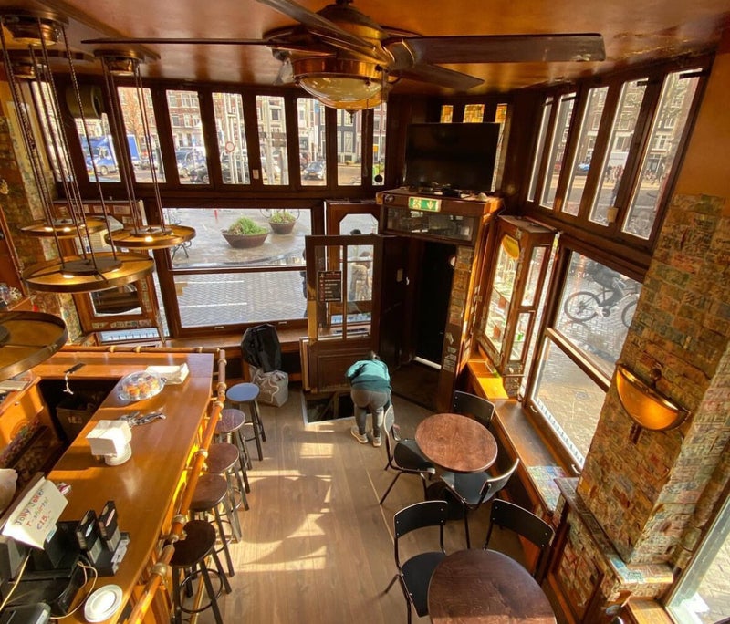 Het houten interieur van Jolly Joker met hoge ramen aan de Nieuwmarkt